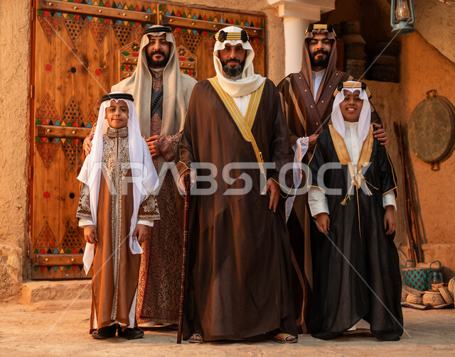الوقوف في أحد البيوت التراثية الطينية ،يوم بدينا 1727 م ،النظر إلى الكاميرا بتعابير السرور، المحبة بين افراد الأسرة ،ذكرى تأسيس الدولة السعودية الأولى 22 فبراير ،مجموعه من الرجال العرب الخليجيون السعوديون مع أبنائهم يرتدون الأزياء الشعبية في الأعياد الوطنية