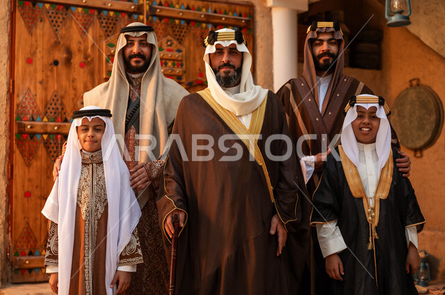 الوقوف في أحد البيوت التراثية الطينية ،يوم بدينا 1727 م ،النظر إلى الكاميرا بتعابير السرور، المحبة بين افراد الأسرة ،ذكرى تأسيس الدولة السعودية الأولى 22 فبراير ،مجموعه من الرجال العرب الخليجيون السعوديون مع أبنائهم يرتدون الأزياء الشعبية في الأعياد الوطنية