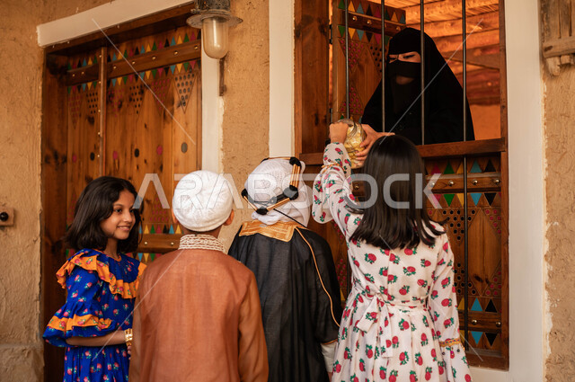 ايماءات السرور والفرح بالاحتفال في ذكرى تأسيس الدولة السعودية الأولى 22 فبراير, يوم بدينا 1727م, ارتداء الأزياء الشعبية التقليدية في الأعياد والمناسبات الوطنية, إمرأة عربية خليجية سعودية ترتدي ازياء التأسيس تقوم بتوزيع الحلوى على الاطفال من النافذة