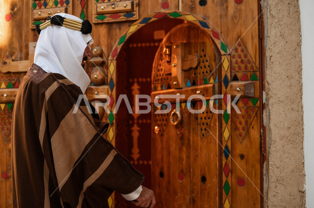 Our Day 1727 AD, the anniversary of the founding of the first Saudi state, February 22, celebration of national holidays and events, the concept of civilization, authenticity and nobility, an old Saudi Gulf Arab man wearing founding costumes, using a crutch, ornate wooden doors