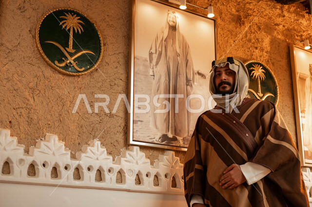 الأعياد والمناسبات الوطنية, ارتداء أزياء التأسيس الشعبية، مشاعر الولاء والانتماء للوطن, يوم بدينا 1727 م، صورة مقربة لرجل عربي خليجي سعودي يقف بفخر وينظر لصورة الملك عبد العزيز آل سعود, ذكرى تأسيس الدولة السعودية الاولى 22 فبراير