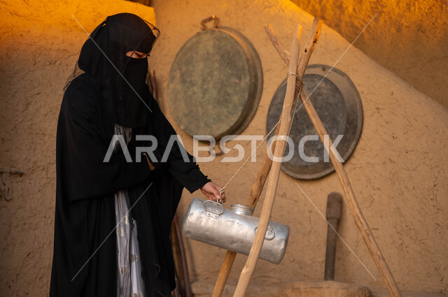 How to make ghee and butter in the past, women’s professions and handicrafts, Fat Day 1727 AD, lifestyle in popular traditional mud houses, a Saudi Gulf Arab woman wearing a burqa and black abaya holding a milk churn in her hand, the anniversary of the founding of the first Saudi state, February 22