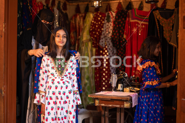 خياطة القماش على الماكينة اليدوية، المحلات التجارية التراثية، حرف ومهن تقليدية نسائية, فتاة عربية سعودية خليجية تقوم بقياس الفستان، امرأة ترتدي العباءة والبرقع تصمم الأزياء الشعبية للمناسبات الوطنية، ذكرى تأسيس الدوله السعوديه الاولى 22 فبراير، يوم بدينا 1727 م