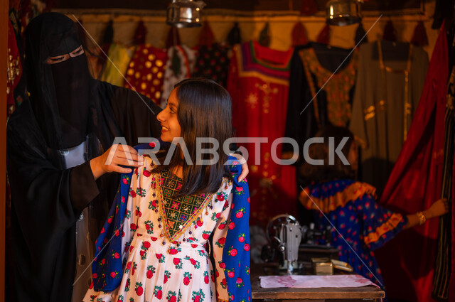 المحلات التجارية التراثية، حياكة القماش على الماكينة اليدوية، حرف ومهن تقليدية نسائية, فتاة عربية سعودية خليجية تقوم بقياس الفستان بمساعدة الخياطة، تصميم الأزياء الشعبية للمناسبات الوطنية، ذكرى تأسيس الدوله السعوديه الاولى 22 فبراير، يوم بدينا 1727 م