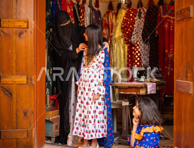 يوم بدينا 1727 م، المحلات التجارية التراثية، حياكة القماش على الماكينة اليدوية، حرف ومهن تقليدية نسائية, فتاة عربية سعودية خليجية تقوم بقياس الفستان بمساعدة الخياطة، تصميم الأزياء الشعبية للمناسبات الوطنية، ذكرى تأسيس الدوله السعوديه الاولى 22 فبراير