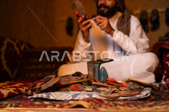 الصناعات والحرف المتوارثة من الأجداد, ممارسة المهن الشعبية التقليدية وإحياء التراث الخليجي, اسكافي عربي خليجي سعودي يرتدي الزي التقليدي يقوم بإصلاح الأحذية باستخدام الأدوات المناسبة, يوم بدينا 1727م, ذكرى تأسيس الدولة السعودية الأولى في 22 فبراير