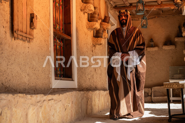 ذكرى تأسيس الدولة السعودية الأولى في 22 فبراير, ارتداء الأزياء الشعبية التقليدية في الأعياد والمناسبات الوطنية, شاب عربي خليجي سعودي يرتدي البشت والعقال يتجول في المناطق التراثية الطينية القديمة, يوم بدينا 1727م, التمسك بالأصالة والتراث السعودي