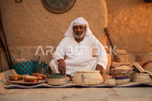 أعمال وصناعات يدوية, إحياء التراث الشعبي الخليجي, الأسواق الأثرية السعودية, رجل كبير بالسن عربي خليجي سعودي يرتدي الزي التقليدي يجلس في إحدى الأحياء الطينية القديمة, يوم بدينا 1727م, ذكرى تأسيس الدولة السعودية الأولى في 22 فبراير