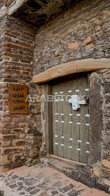 الفن الهندسي المعماري على الطراز القديم للمباني والمنازل المبنية من الحجارة، لوحه حجرة تخزين حبوب العشر في قرية آل ينفع في مركز تمنية في منطقة عسير في المملكة العربية السعودية، باب خشبي قديم في إحدى القرى التراثية، معالم و أماكن أثرية قديمة في المدن التاريخيه