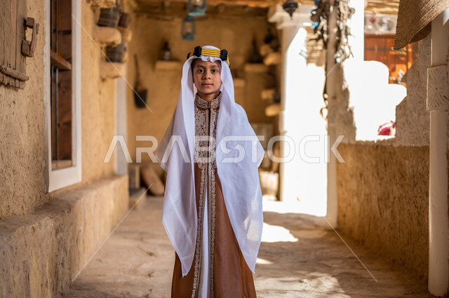 تعليم الأولاد الفخر والاعتزاز بالانتماء للوطن، أسلوب الحياة القديمة، يوم بدينا 1727 م، ارتداء الأزياء الشعبيه في المناسبات الوطنية، ذكرى تأسيس الدولة السعودية 22 فبراير، ولد عربي خليجي سعودي يرتدي العقال والبشت ينظر إلى الكاميرا بإيماءات الثقة بالنفس 