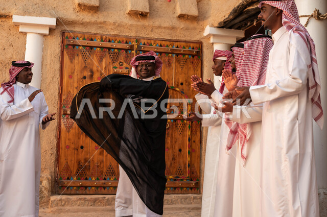 مجموعة من الرجال العرب الخليجيين السعوديين يقومون بالغناء والرقص احتفالا بيوم بدينا١٧٢٧، الاحياء التراثية الطينية القديمة، عروض فرق الفلكلور التراثي في المناسبات الوطنية، ارتداء الأزياء الشعبية التقليدية والبشت في المناسبات، ذكرى تأسيس الدولة السعودية الأولى