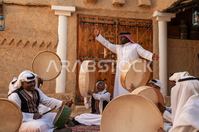 فرقة رجال عرب خليجيين سعوديين يقومون بالاحتفال بذكرى تأسيس الدولة السعودية الأولى، الغناء والاندماج مع الرقص الشعبي وقرع الطبول احتفالا بيوم بدينا ١٧٢٧، إظهار الولاء والحب للدولة السعودية، الأحياء التراثية الطينية القديمة، ارتداء ازياء العرضه النجدية