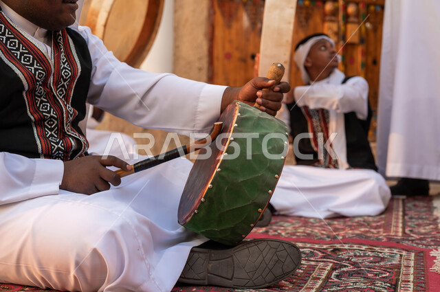 المشاركة في الفعاليات والأعياد والمهرجانات الشعبية، إظهار الولاء والحب للدولة السعودية، الأحياء الطينية القديمة، صورة مقربة ليدين رجل عربي خليجي سعودي يقوم بقرع الطبول احتفالا بيوم بدينا١٧٢٧، ارتداء الأزياء الشعبية التقليدية التراثية في المناسبات الوطنية