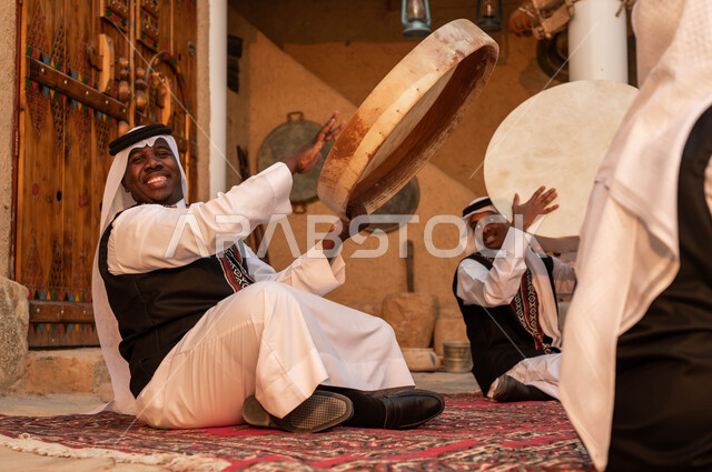 رجل عربي خليجي سعودي يقوم بالاحتفال بتأسيس الدولة الأولى، الاندماج مع الرقص الشعبي وقرع الطبول احتفالا بيوم بدينا ١٧٢٧، إظهار الولاء والحب للدولة السعودية، الأحياء التراثية الطينية القديمة، ارتداء ازياء العرضه النجدية، عروض الفلكلور الشعبي