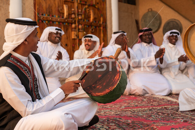 الاندماج مع الرقص الشعبي وقرع الطبول احتفالا بيوم بدينا ١٧٢٧، إظهار الولاء والحب للدولة السعودية، صورة مقربة من الجانب لرجل عربي خليجي سعودي يقوم بقرع الطبول احتفالا بتأسيس الدولة الأولى، الأحياء التراثية الطينية القديمة، ارتداء ازياء العرضه النجدية