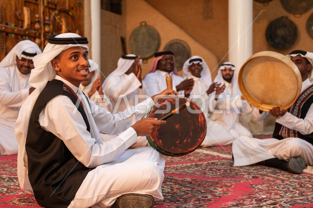حب الوطن والاعتزاز به, والاندماج مع الرقص الشعبي وقرع الطبول في يوم بدينا 1727,مجموعة من الرجال العرب السعوديين الخليجيين يرتدون زي العرضة يقومون بقرع الطبول والاحتفال تخليدا ليوم تأسيس الدولة السعودية 22 فبراير, ارتداء الازياء الشعبية احتفالا بالمناسبات الوطنية