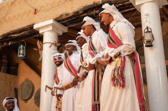 الاحياء التراثية الطينية القديمة, فرقة عروض الفلكلور التراثي في المناسبة الوطنية في 22 فبراير, مجموعة من الرجال العرب السعويين الخلييجين برتدون الزي التقليدي, ارتداء الازياء الشعبية في لمناسبات الوطنية, الرقص والاهازيج احتفالا بيوم بدينا 1727