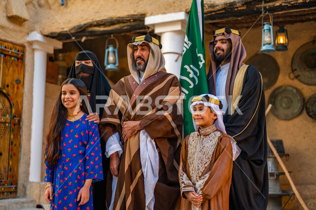 Heritage houses built of mud in the old style, the anniversary of the founding of the first Saudi state, February 22, a Saudi Gulf Arab family wearing popular costumes on holidays and national occasions, standing with gestures of pride and dignity, Day of Our Day 1727 AD