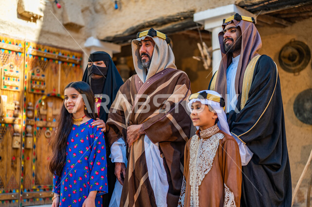 Heritage houses built of mud in the old style, the anniversary of the founding of the first Saudi state, February 22, a Saudi Gulf Arab family wearing popular costumes on holidays and national occasions, standing with gestures of pride and dignity, Day of Our Day 1727 AD