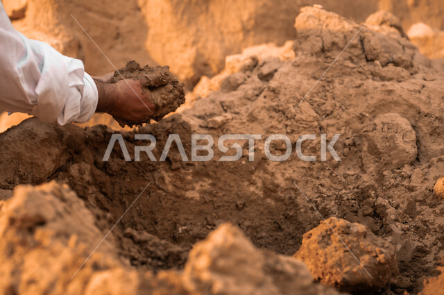 حب الوطن والتمسك بالأصالة والتراث السعودي, إعادة بناء وترميم البيوت والمنشآت القديمة, صورة مقربة ليد شاب عربي خليجي سعودي يرتدي الثوب التقليدي يمسك بيده حفنة من التراب, يوم بدينا 1727م, ذكرى تأسيس الدولة السعودية الأولى في 22 فبراير