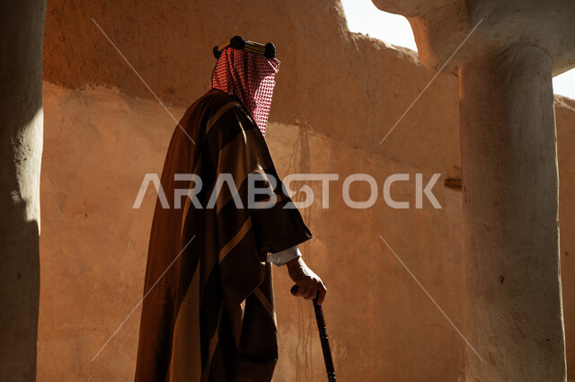 ذكرى تأسيس الدولة السعودية الأولى في 22 فبراير, التجول بالأحياء والمنشآت الطينية التراثية القديمة, صورة من الجانب الرجل عربي خليجي سعودي يرتدي البشت والعقال يحمل العكاز, ارتداء الأزياء الشعبية التقليدية في الأعياد والمناسبات الوطنية, يوم بدينا 1727 م