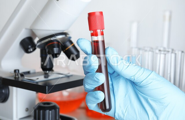انابيب زجاجية مليئة بالدم داخل المختبرات الطبية،اجراء التحاليل الدموية، مفهوم الكيمياء الحيوية, صورة مقربة ليد ترتدي القفازات تحمل أنبوب الاختبار للقيام بالتجارب في المختبر ،التفاعلات الكيميائية الفعالة، مفهوم الطب والرعاية الصحيه