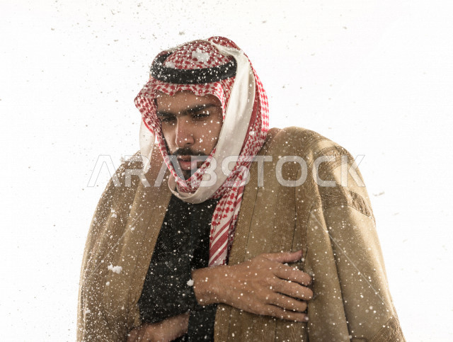بورتريه لرجل سعودي خليجي بإيماءات الوجه التي تدل على الشعور بالبرد ، يرتدي ملابس شتوية مناسبة لفصل الشتاء ، خلفية بيضاء
