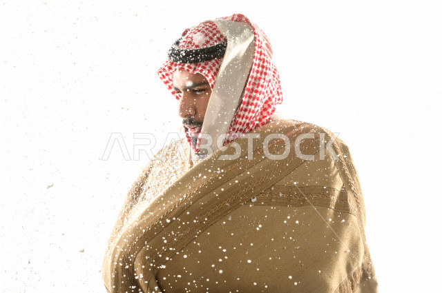 بورتريه لرجل سعودي خليجي بإيماءات الوجه التي تدل على الشعور بالبرد ، يرتدي ملابس شتوية مناسبة لفصل الشتاء ، خلفية بيضاء