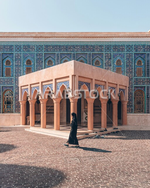 الفن الهندسي المعماري على الطراز الإسلامي الحديث، إمرأة عربية خليجية محجبة ترتدي العباءة السوداء تتجول حول مسجد قرية كتارا في مدينة الدوحة، آداء الفرائض والصلوات, العبادة والتقرب إلى الله, معالم دينية إسلامية مشهورة, أماكن تاريخية تراثية ثقافية