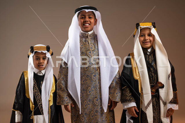 النظر إلى الكاميرا بتعابير السرور, يوم بدينا 1727 م، تعليم الأبناء الفخر والاعتزاز بالهوية الوطنية، بورتريه مقرب لمجموعة أولاد عرب خليجيين سعوديين يرتدون الزي التقليدي الشعبي، ذكرى تأسيس الدولة السعودية 22 فبراير، خلفية بيج