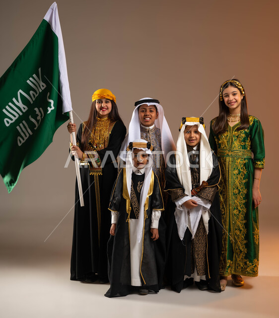 Raising the founding flag with pride and dignity, inheriting love for the homeland from the ancestors, a portrait of a group of Saudi Gulf Arab boys wearing traditional folk costumes, expressing loyalty to the country, Day of Our Day 1727 AD, the anniversary of the founding of the first Saudi state on February 22, full body portrait, beige background