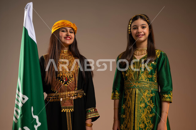 اللطافة والأنوثة والبراءة, يوم بدينا 1727 م، الوقوف بجانب علم التأسيس والنظر إلى الكاميرا، ارتداء أزياء المنطقة الوسطى والجنوبية في المناسبات الوطنية، بورتريه لبنتين عربيتين خليجيتين ترتديان الزي الشعبي في ذكرى تأسيس الدولة السعودية 22 فبراير، خلفية بيج