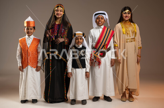 تعليم الأبناء الفخر والاعتزاز بأنجازات الوطن، يوم بدينا 1727 م، النظر إلى الكاميرا بتعابير الفرح والسرور، بورتريه لمجموعة أولاد عرب خليجيين سعوديين يرتدون الأزياء الشعبية التقليدية،  ذكرى تأسيس الدولة السعودية 22 فبراير، صورة الجسم بالطول الكامل، خلفية بيج