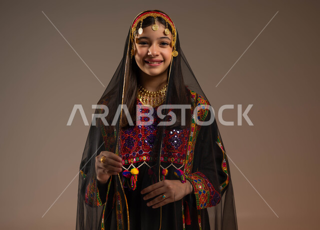 الفخر بالتراث التاريخي والحضاري، ذكرى تأسيس الدولة السعودية 22 فبراير، يوم بدينا 1727 م، ارتداء أزياء المنطقة الوسطى، بورتريه مقرب لفتاة عربية خليجية سعودية مبتسمة ترتدي الهامة والبشت والكرتة تنظر إلى الكاميرا بإيماءات الأنوثة والنعومة، خلفية بيج