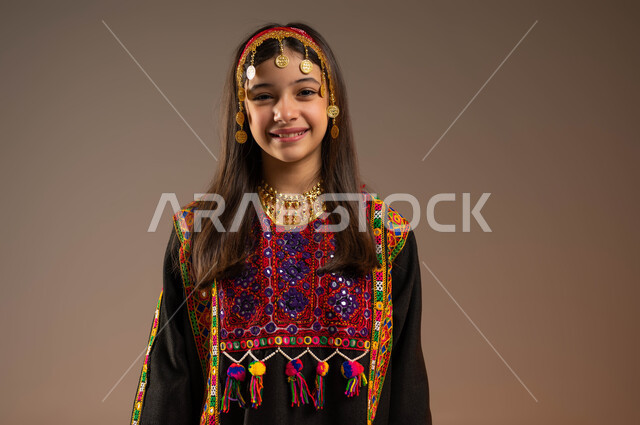 الفخر بالتراث التاريخي والحضاري، ذكرى تأسيس الدولة السعودية 22 فبراير، يوم بدينا 1727 م، ارتداء أزياء المنطقة الوسطى في المناسبات الوطنية، بورتريه مقرب لفتاة عربية خليجية سعودية مبتسمة ترتدي الهامة والكرتة تنظر إلى الكاميرا بإيماءات الأنوثة والنعومة، خلفية بيج