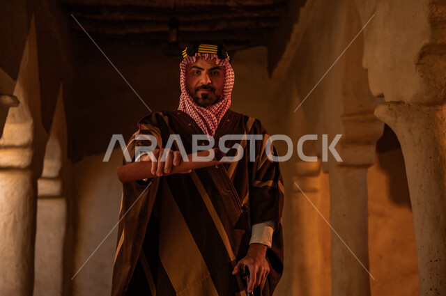 Pride in the country’s authenticity and history, the anniversary of the founding of the first Saudi state, February 22, a close-up photo of a Saudi Gulf Arab man wearing a bisht and shemagh, holding in his hand the archaeological letters of King Abdulaziz in one of the mud houses, preserving historical antiquities and manuscripts, Day of Dina 1727 AD.