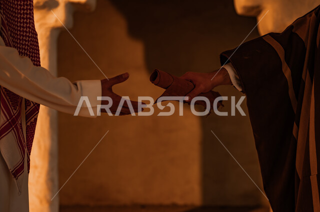 توارث الأثار والمخطوطات بين أبناء الوطن، الأحياء والبيوت التراثية الطينية القديمة، صورة مقربة ليد رجل عربي خليجي سعودي يرتدي البشت يعطي رسائل الملك عبد العزيز الى شاب يرتدي الزي التقليدي، يوم بدينا 1727 م، ذكرى تأسيس الدولة السعودية الأولى 22 فبراير