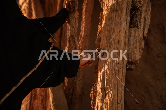 يوم بدينا 1727 م, ذكرى تأسيس الدولة السعودية الأولى في 22 فبراير، ارتداء الأزياء الشعبية في الاعياد الوطنية، الفخر والاعتزاز بالأثار التاريخية, صورة مقربة ليد إمرأة عربية خليجية سعودية ترتدي العباءة السوداء تمسك يد باب خشبي في إحدى البيوت التراثية القديمة