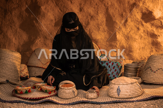 منتجات ومحاصيل محلية وطنية سعودية، ذكرى تأسيس الدولة السعودية الأولى 22 فبراير، يوم بدينا 1727 م، إمرأة عربية خليجية سعودية ترتدي البرقع العباءة السوداء تجلس على الحصيرة تقوم ببيع البقوليات في حي شعبي تراثي، مهن وأعمال نسائية قديمة، وضع الحبوب في سلل من القش