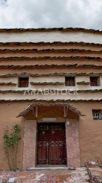 المباني و المنازل المبنية على الطراز القديم في منطقة عسير في السعودية في وقت النهار، الفن الهندسي المعماري للمعالم و الأماكن الأثرية القديمة في المدن التاريخيه، السماء الملبدة بالغيوم