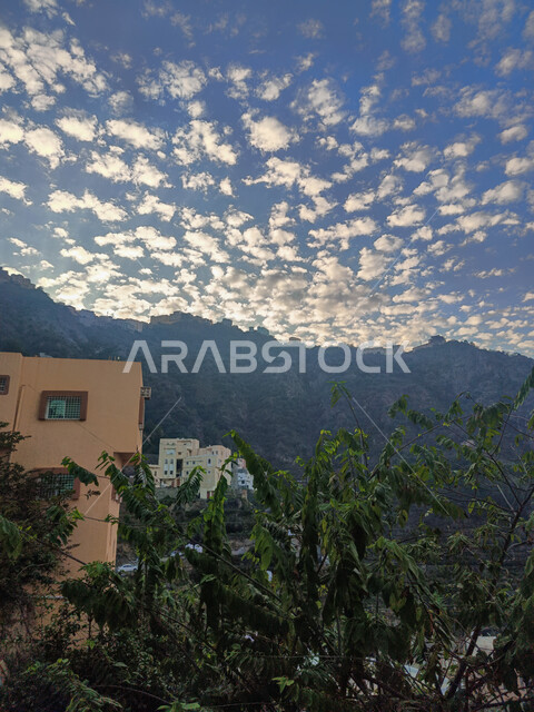 منظر الغيوم البيضاء في السماء وقت غروب الشمس، المباني السكنية والبيوت الاثرية القديمة في جبال محافظة فيفاء في جازان، معالم وأماكن سياحية طبيعية في المملكة العربية السعودية، المدرجات الزراعية الخضراء والاشجار على القمم والمرتفعات الجبلية