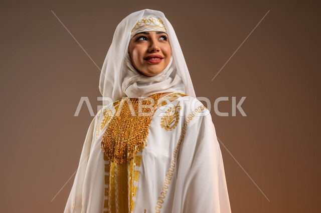 ذكرى تأسيس الدولة السعودية الأولى في 22 فبراير، الوقوف باستقامة والنظر إلى شيء ما بتعابير الثقة الفخر، ارتداء زي المنطقة الشرقية في المناسبات والأعياد الوطنية، بورتريه مقرب لإمرأة عربية خليجية سعودية مبتسمة ترتدي الشيلة والنشل في يوم بدينا 1727 م، خلفية بيج