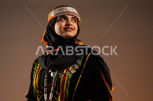 ذكرى تأسيس الدولة السعودية الأولى في 22 فبراير، الوقوف باستقامة والنظر إلى شيء ما بتعابير الثقة الفخر، ارتداء الازياء الشعبية في المناسبات والأعياد الوطنية، بورتريه مقرب لإمرأة عربية خليجية سعودية مبتسمة ترتدي زي المنطقة الوسطى في يوم بدينا 1727 م، خلفية بيج