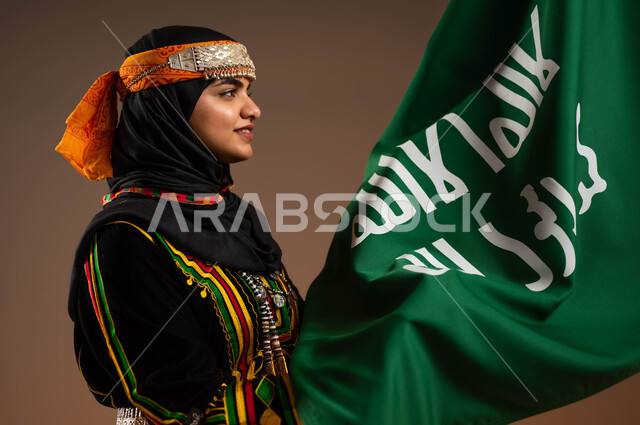 مفهوم حب الوطن والارتباط به, النظر الى علم تأسيس الدولة السعودية الأولى 22 فبراير، ذكرى يوم بدينا 1727 م، ارتداء زي المنطقة الوسطى في المناسبات الوطنية، بورتريه لإمرأة عربية خليجية سعودية مبتسمة تمسك بيدها علم التأسيس, الاعتزاز بالبلد والانتماء اليه، خلفية بيج