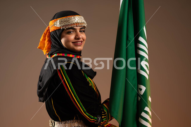 ارتداء الأزياء الشعبية التقليدية, رفع علم التأسيس بإيماءات الثقة و الفخر بانجازات الوطن، بورتريه مقرب لامرأة عربية خليجية سعودية ترتدي زي المنطقة الوسطى، ذكرى تأسيس الدولة السعودية الأولى ٢٢ فبراير، مفهوم حب الوطن والارتباط به، يوم بدينا١٧٢٧م,  خلفية بيج