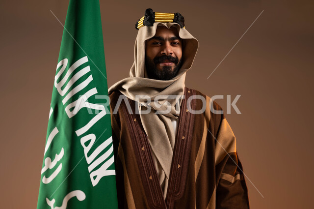 يوم بدينا ٢٢فبراير، ايماءات الفخر والاعتزاز بالهوية العربية، بورتريه مقرب لرجل عربي خليجي سعودي مبتسم يرتدي العقال الذهبي والدقلة والغترة، المشاركة في الاحتفالات والمناسبات الوطنية، رفع علم التأسيس بتباهي واعتزاز، ذكرى تأسيس الدولة السعودية الأولى١٧٢٧م، خلفية بيج