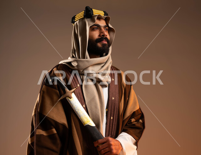 Wearing traditional folk costumes and looking at a place with gestures of pride, Day of Dina 1727 AD, close-up portrait of a Saudi Gulf Arab young man wearing a golden iqal, dhikla and ghutra carrying a sword, manhood and chivalry among the Arabs, anniversary of the founding of the first Saudi state on February 22, beige background