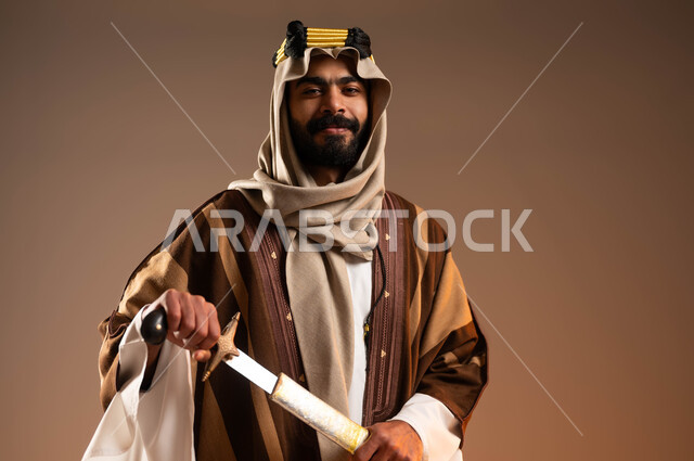 مفهوم الاصالة والعراقة، الرجولة والشهامة عند العرب، يوم بدينا1727م، ارتداء الأزياء الشعبية،  بورتريه مقرب لشاب عربي خليجي سعودي يرتدي العقال الذهبي والدقلة والغترة يقوم باخراج السيف من غمده، ذكرى تأسيس الدولة السعودية الأولى في 22 فبراير, خلفية بيج،