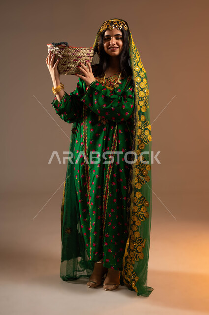 حرف وأعمال شعبية تقليدية، ذكرى تأسيس الدولة السعودية الاولى ٢٢ فبراير، مشغولات يدوية نسائية، بورتريه لشابة عربية خليجية سعودية مبتسمة ترتدي الشيلة والهامة والبشت تحمل سلة مصنوعة من القش، الاحتفال بيوم بدينا ١٧٢٧م، صورة لكامل الجسم، خلفية بيج