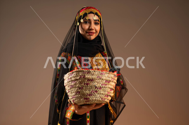 حسن الضيافة والاستقبال عند العرب, مهن وحرف يدوية شعبية, بورتريه مقرب لإمرأة عربية خليجية سعودية ترتدي زي المنطقة الوسطى في المناسبات الوطنية تمسك سلة مصنوعة من القش, يوم بدينا 1727م, ذكرى تأسيس الدولة السعودية الأولى في 22 فبراير, خلفية بيج